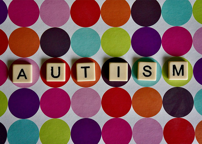 Scrabble tiles spelling AUTISM on a colorful polka dot background, representing new research and understanding the condition. Scrabble tiles spelling AUTISM on a colorful polka dot background, representing new research and understanding the condition.