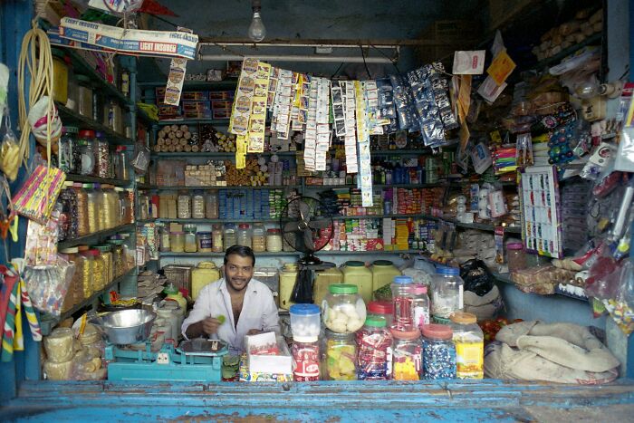 A man smiling and sitting in a small, cluttered convenience store. Craziest plane interactions.