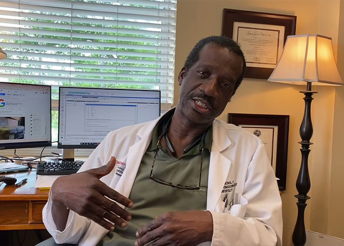 A doctor in a white lab coat sitting at a desk, discussing the catastrophic IVF mix-up and baby truth.