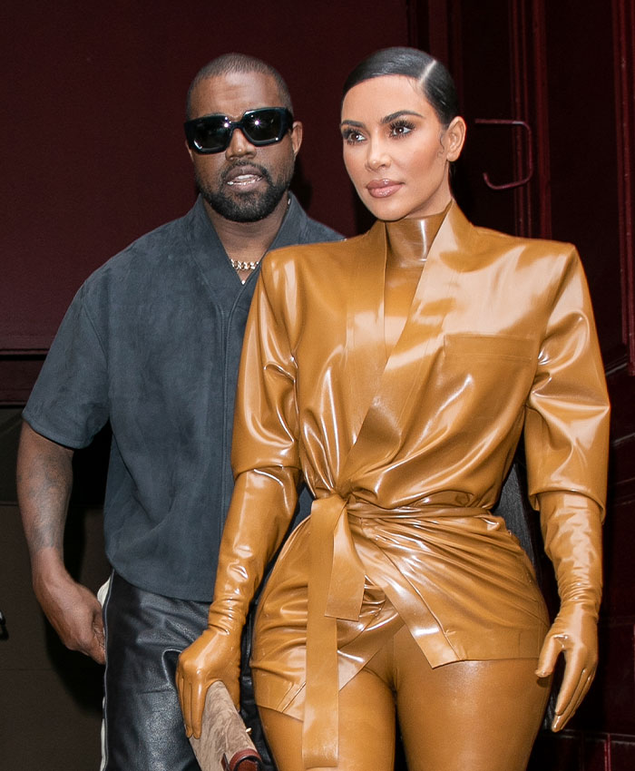 Kim Kardashian in a form-fitting brown outfit next to Kanye West, highlighting their public presence to protect your kids.