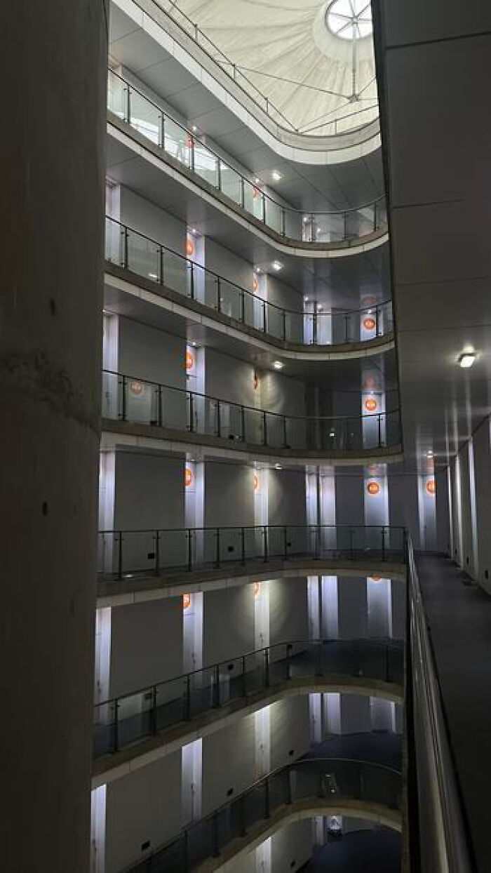 A multi-story circular building interior with balconies and glowing doors, an example of haunting liminal spaces.