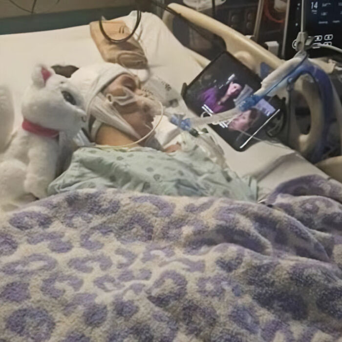 A young girl in a hospital bed with a white stuffed animal beside her, victim of a dangerous social media challenge.