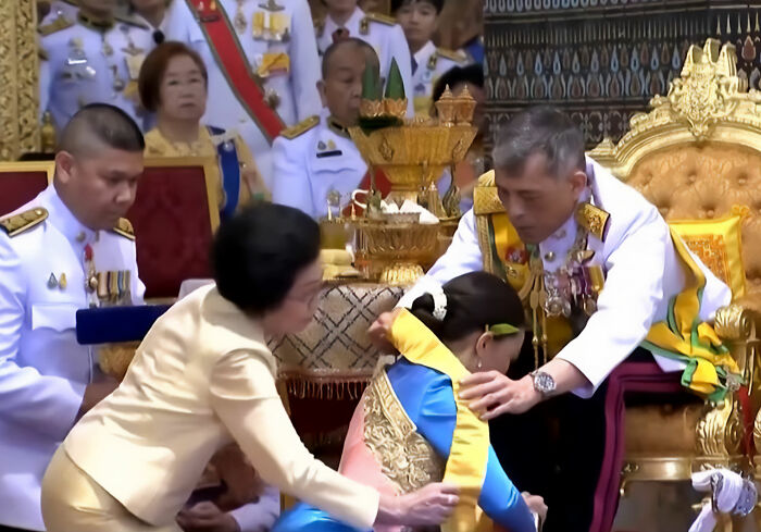 Thai royal family members performing a traditional ceremony indoors Thai royal family members performing a traditional ceremony indoors