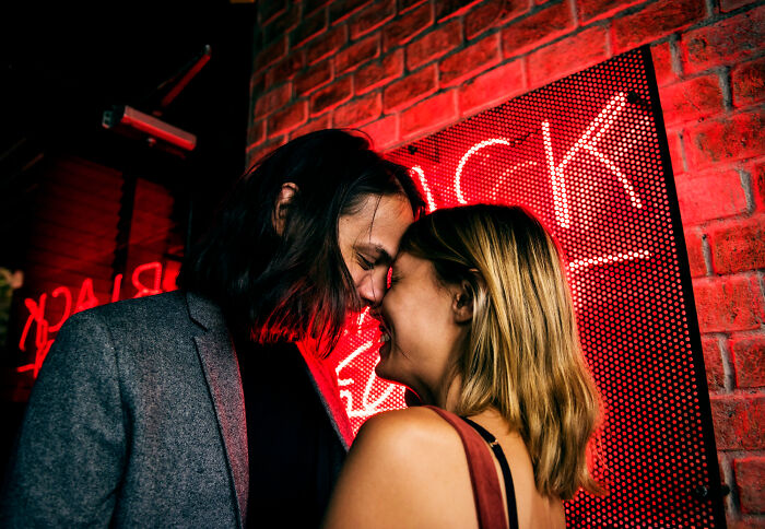 Couple embracing in front of red neon light family secrets