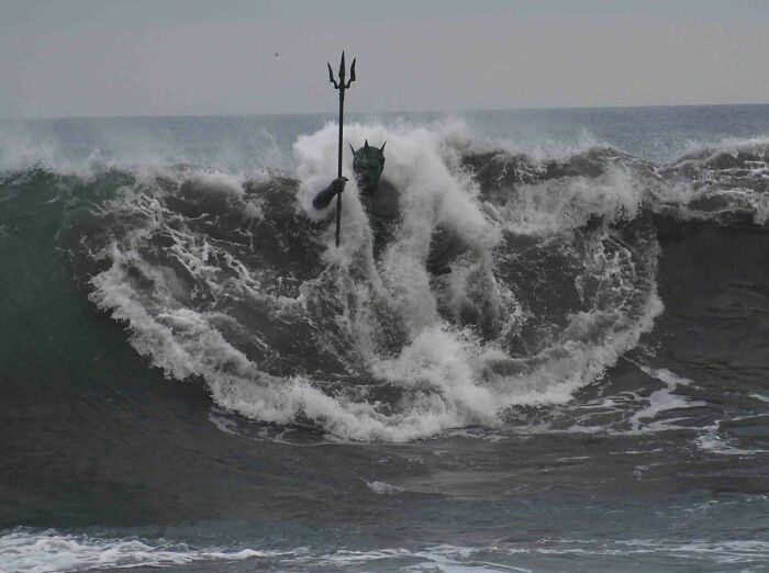 Ocean wave shaped like a trident-wielding figure emerging from the water