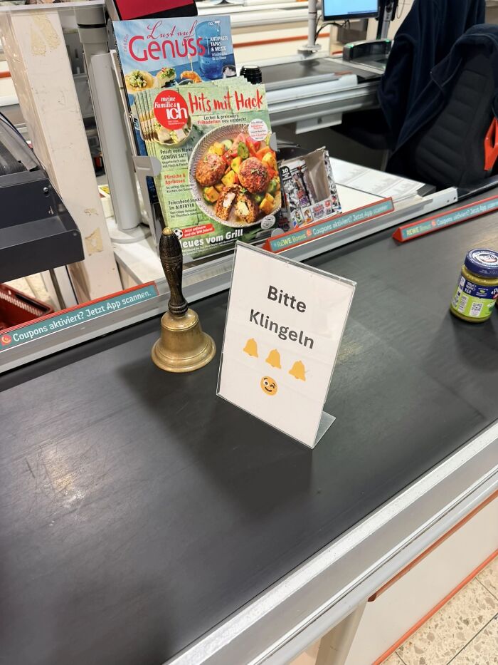 A checkout counter with a bizarre sign reading "Bitte Klingeln" and a bell, raising questions about its use.
