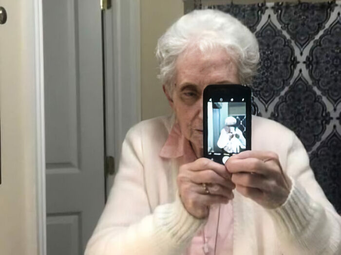 Elderly woman taking a selfie capturing infinite mirror effect