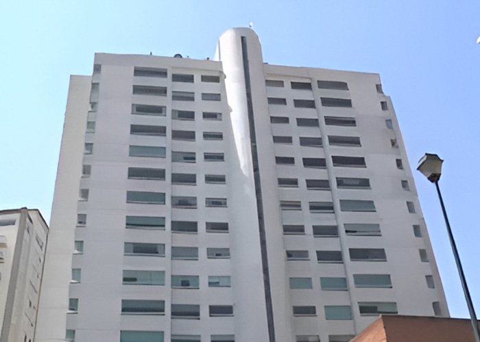 Tall modern white residential building under blue sky
