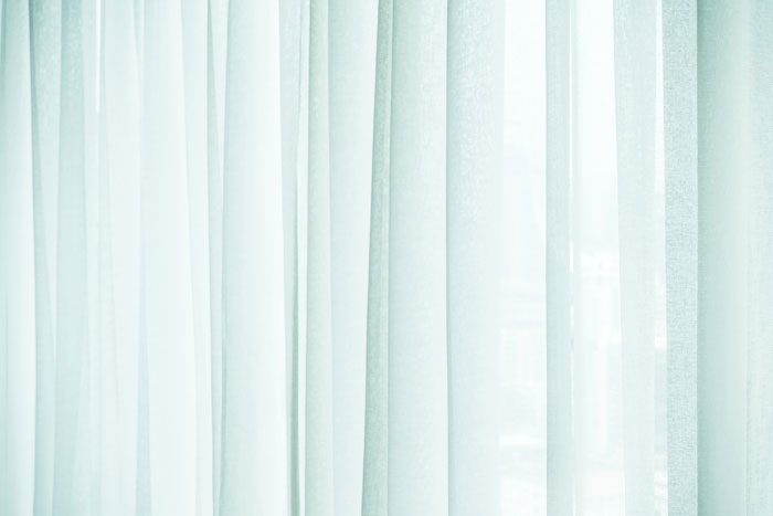Sheer curtains letting in soft natural light through window