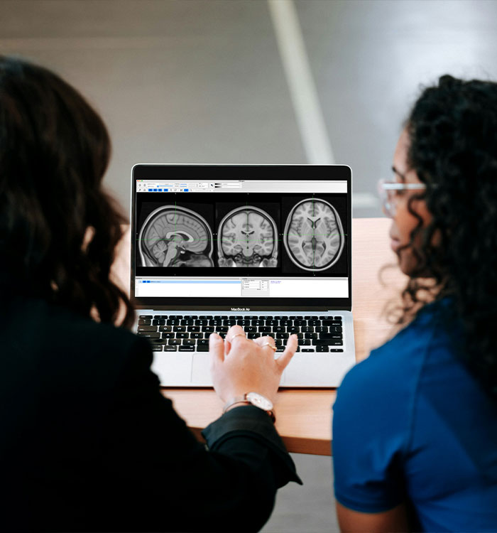 Two women looking at brain scan images on laptop screen Two women looking at brain scan images on laptop screen