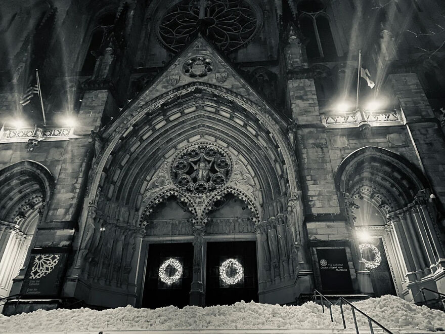 Historic cathedral entrance decorated with wreaths and illuminated lights at night