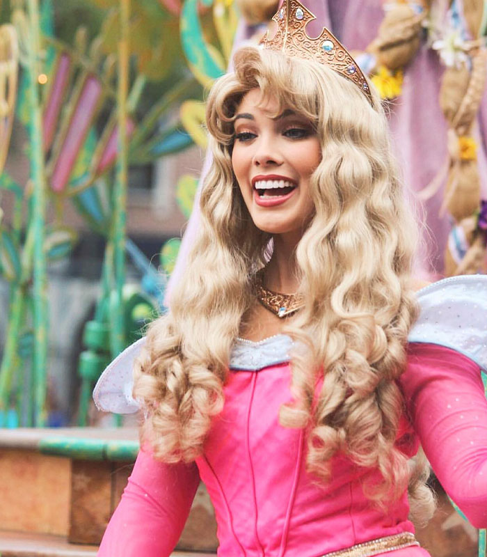 Woman dressed as Disney princess Aurora with crown and pink dress Woman dressed as Disney princess Aurora with crown and pink dress