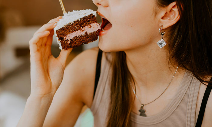 Woman eating a slice of chocolate and cream cake