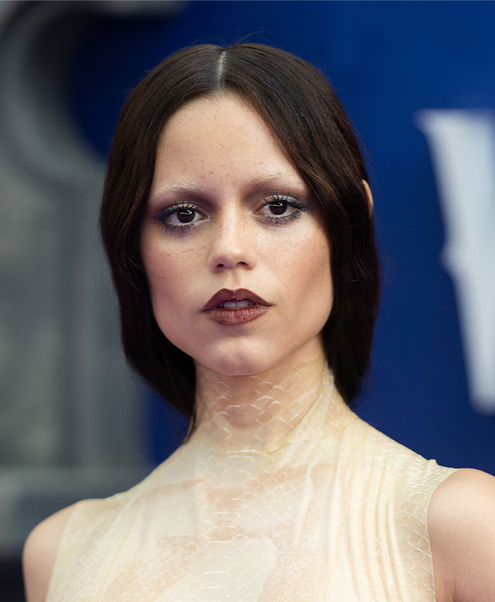 Young woman with dark hair and makeup emphasizing a thin, skeletonized look