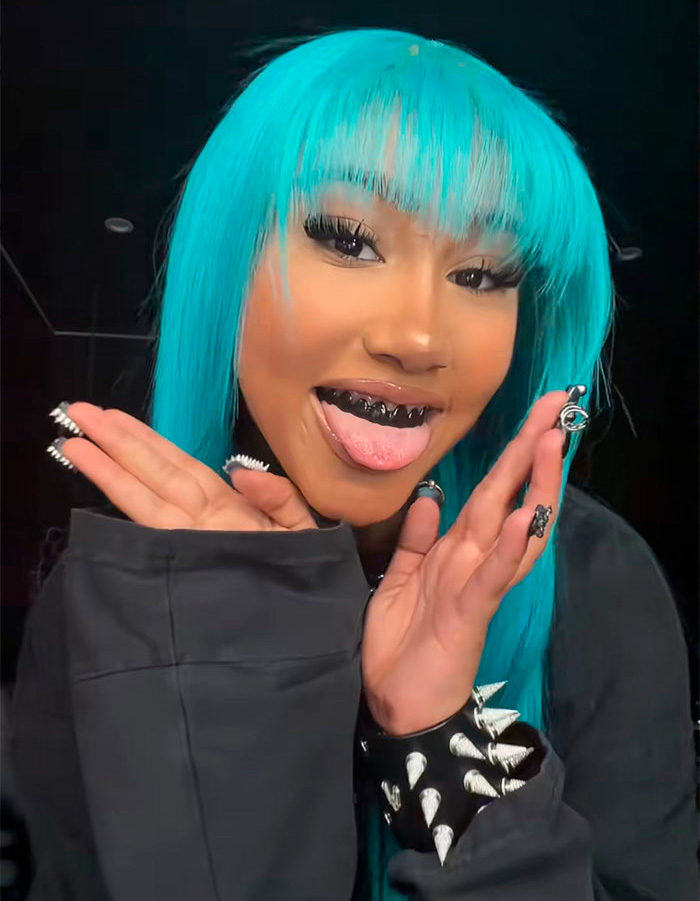 Person with blue hair showing blackened teeth grill with tongue out Person with blue hair showing blackened teeth grill with tongue out