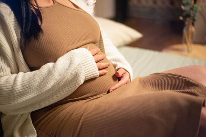 Pregnant woman holding belly in cozy home setting