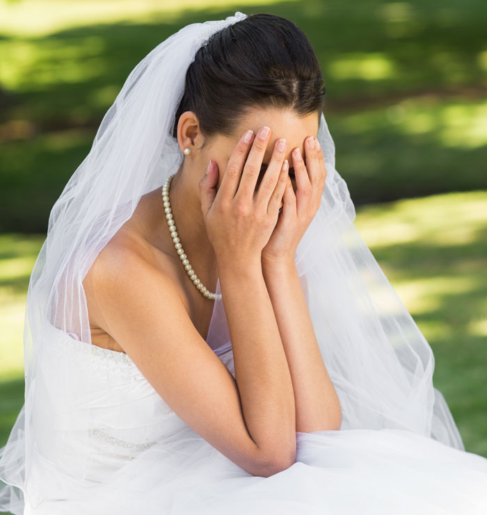 Bride in veil covering face with hands showing wedding emotions