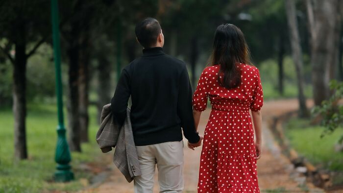 Couple walking hand in hand on a park path contemplating moral dilemmas