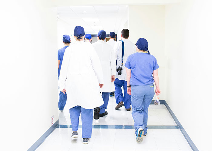 Group of medical specialists walking down a bright hospital hallway Group of medical specialists walking down a bright hospital hallway