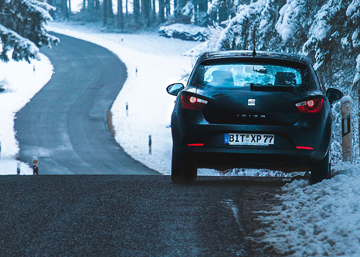 Black car parked on snowy road moment to leave immediately
