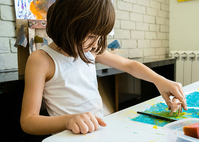 A young girl focused on painting a small toy pig, illustrating conditions like autism and brain triggers. A young girl focused on painting a small toy pig, illustrating conditions like autism and brain triggers.