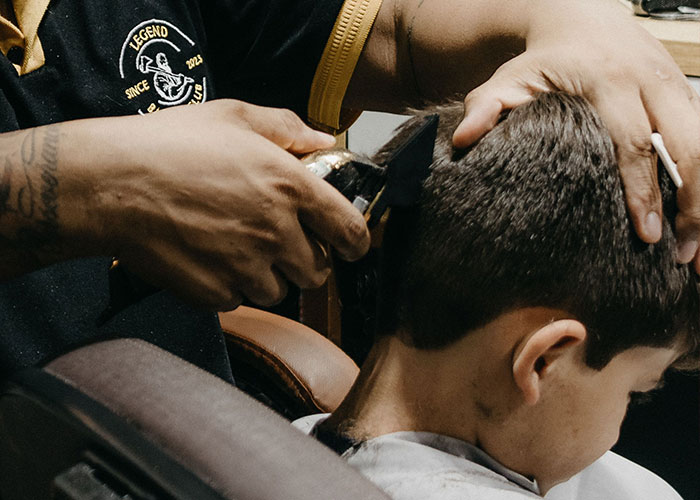 A child getting a haircut from a barber, symbolizing moments when kids cant keep contact with parents.