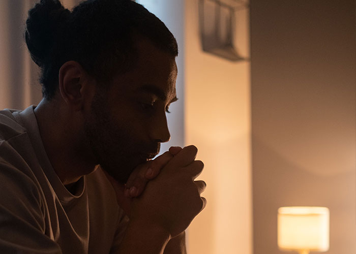 A man looking down in contemplation, reflecting on things close friends commit that broke people's trust forever.