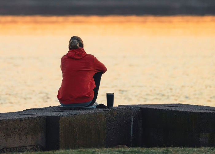 A woman sits alone by the water, contemplating family and socially unacceptable advice.