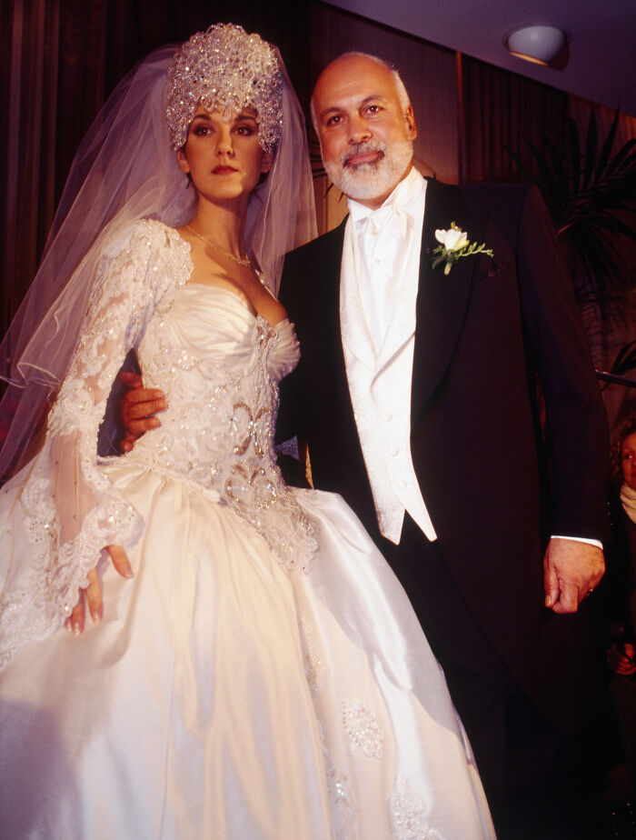 Celine Dion in an elaborate, embellished wedding dress with a dramatic headpiece and Rene Angelil.