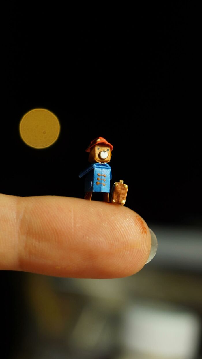 Tiny Paddington Bear miniature paper figure standing on a fingertip, displaying immense detail.