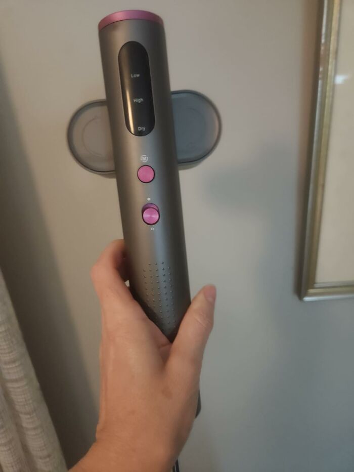 A hand holding a gray hair styling tool with pink buttons, one of the home finds on sale for Prime Day.