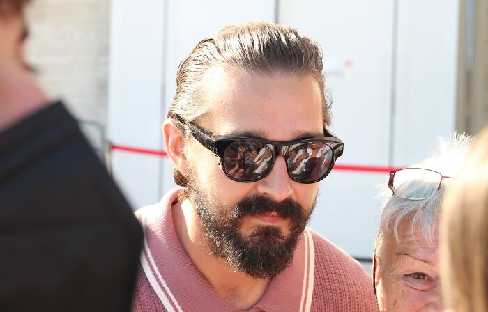 Celebrity with a beard and slicked-back hair, wearing sunglasses and a pink shirt. Has this celebritys fame run out?