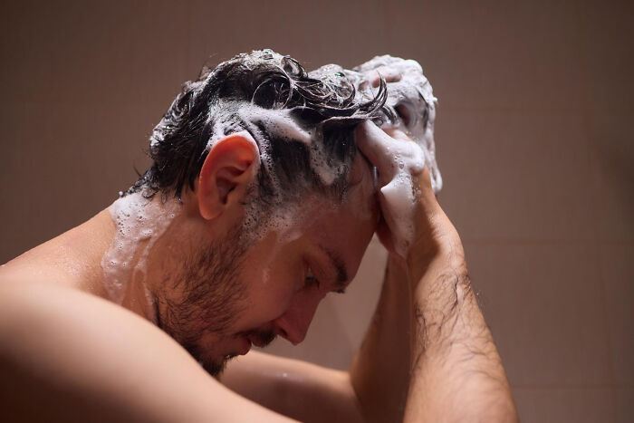 Man washing hair with shampoo as a cleansing ritual after ex cheating