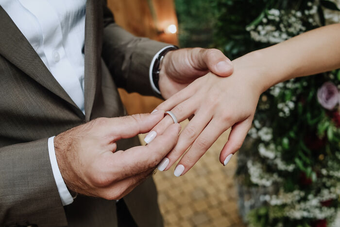 Close up of man putting ring on woman's finger in romantic relationship context