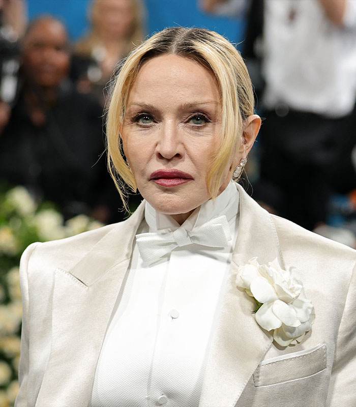 Madonna at Paris Fashion Week in a white suit, showing a wardrobe malfunction.