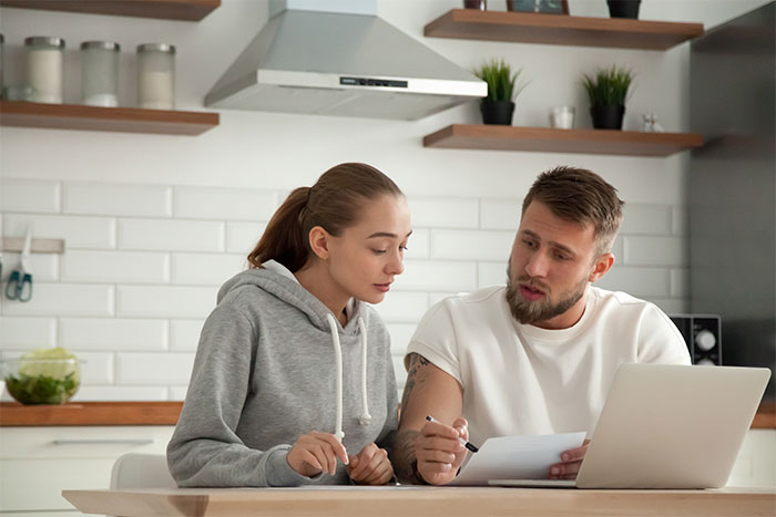 Couple discussing wedding plans with a laptop and paperwork