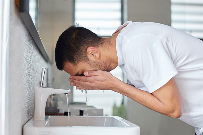 A person is violently sick after MIL&rsquo;s birthday dinner, splashing water on their face over a sink.