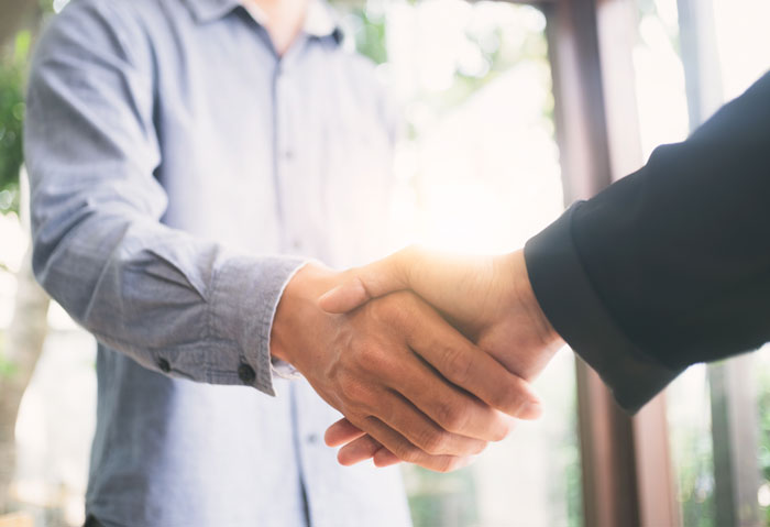 Two people shaking hands symbolizing a professional interaction Two people shaking hands symbolizing a professional interaction