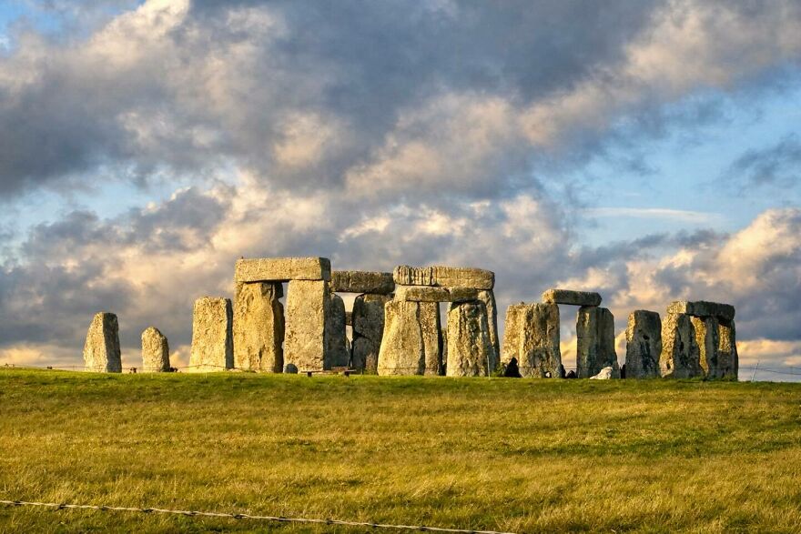 Stonehenge standing stones on grassy field under a dramatic cloudy sky