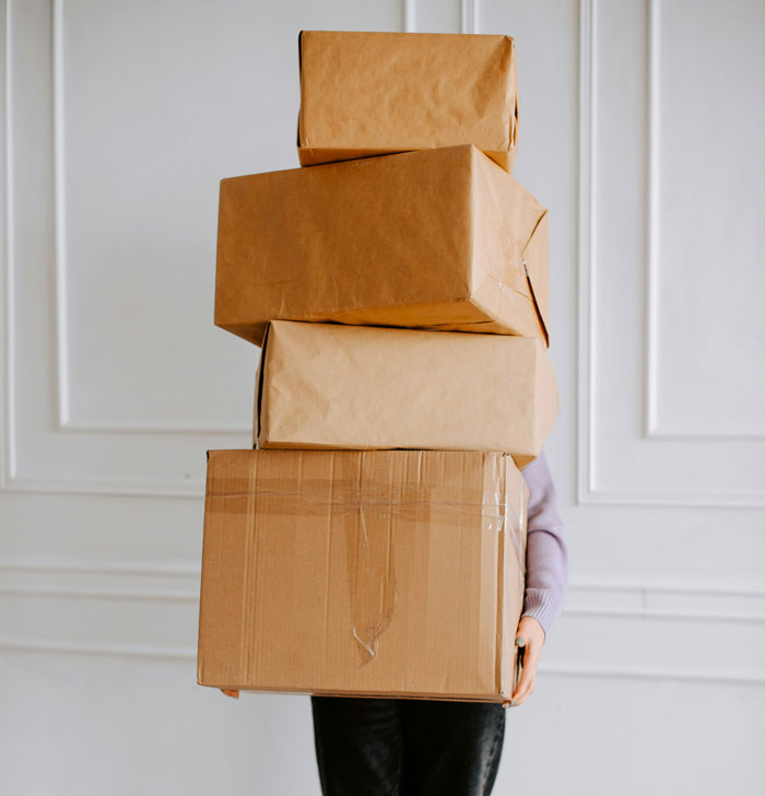 Person holding stack of cardboard boxes for moving or delivery