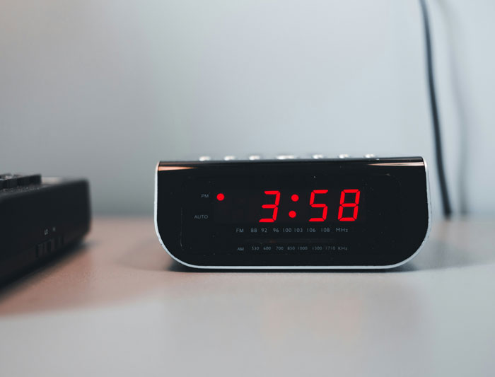 Digital clock radio showing time 3:58 on table