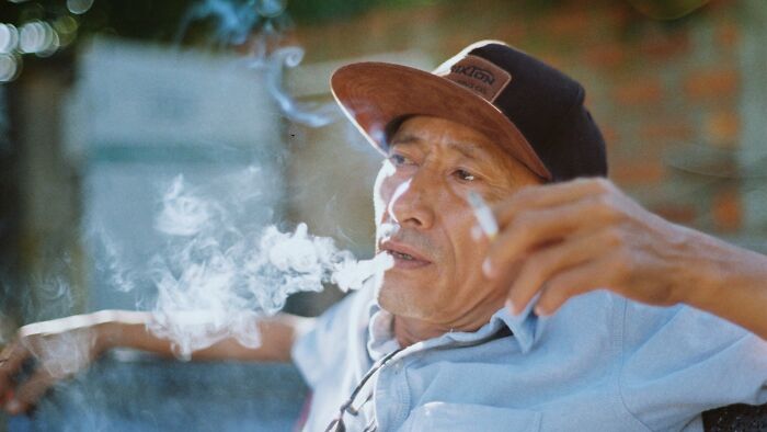 Man smoking cigarette with relaxed expression outdoors