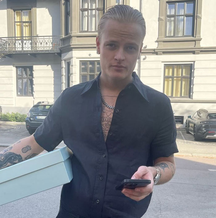 Norwegian Crown Princess's son in casual clothes holding a box and phone outdoors Norwegian Crown Princess's son in casual clothes holding a box and phone outdoors