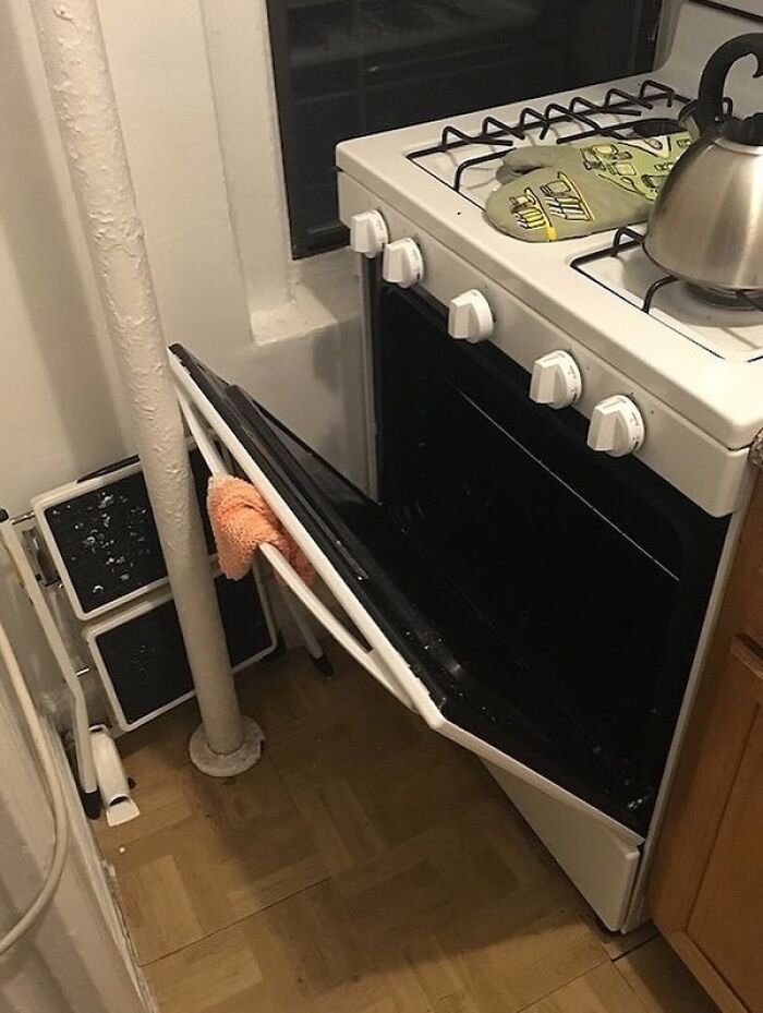 Kitchen oven door blocked from opening fully by nearby pipe