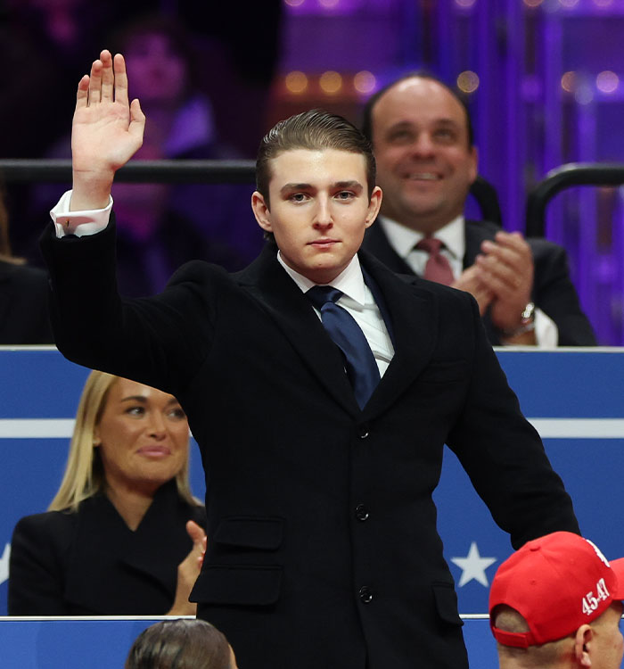 Barron Trump raising hand at UFC event wearing a dark suit Barron Trump raising hand at UFC event wearing a dark suit