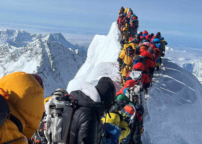 Crowd of climbers on a narrow ridge of Mount Everest, a common sight past the frozen body of Green Boots.