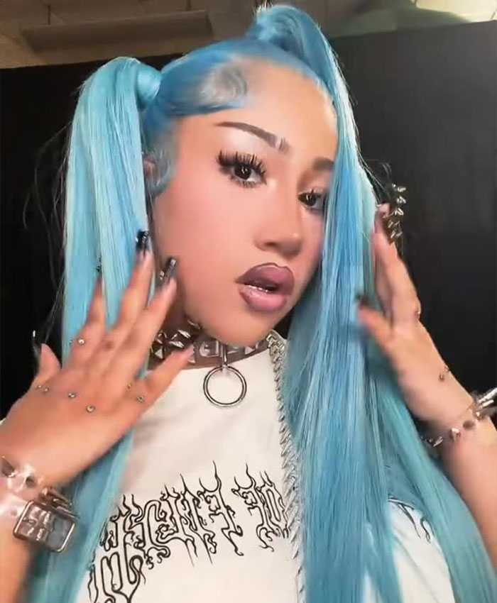 A woman with vibrant blue hair and bold makeup, wearing a studded choker.