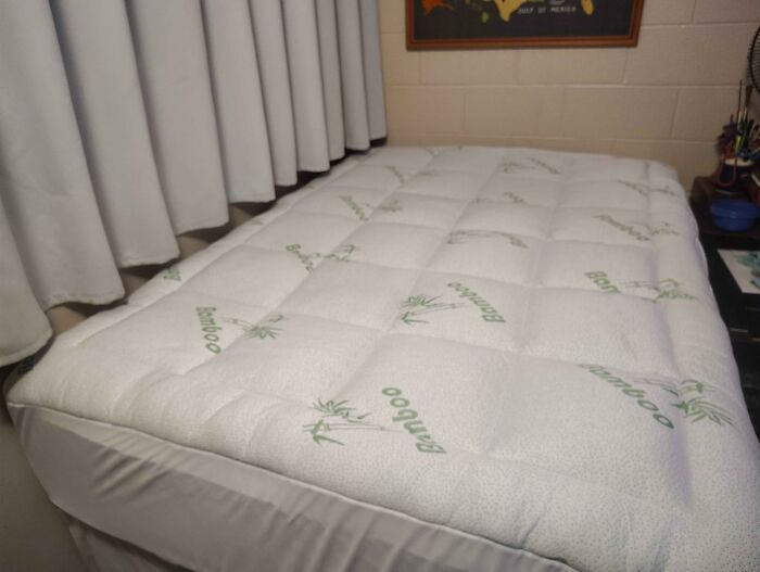 A white quilted mattress topper with green bamboo prints, a cozy home find on Prime Day, on a bed.