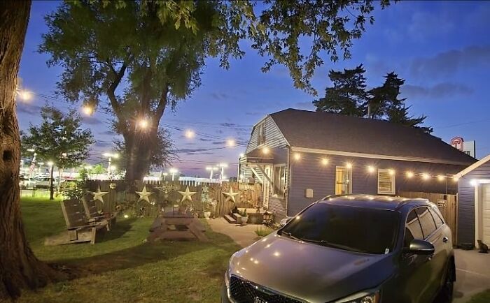 Charming house with a decorated outdoor and backyard area, lit with string lights for summer evenings.