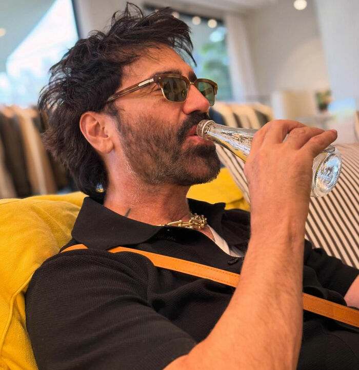 Man drinking from a glass bottle reflecting World Cup opening ceremony headline